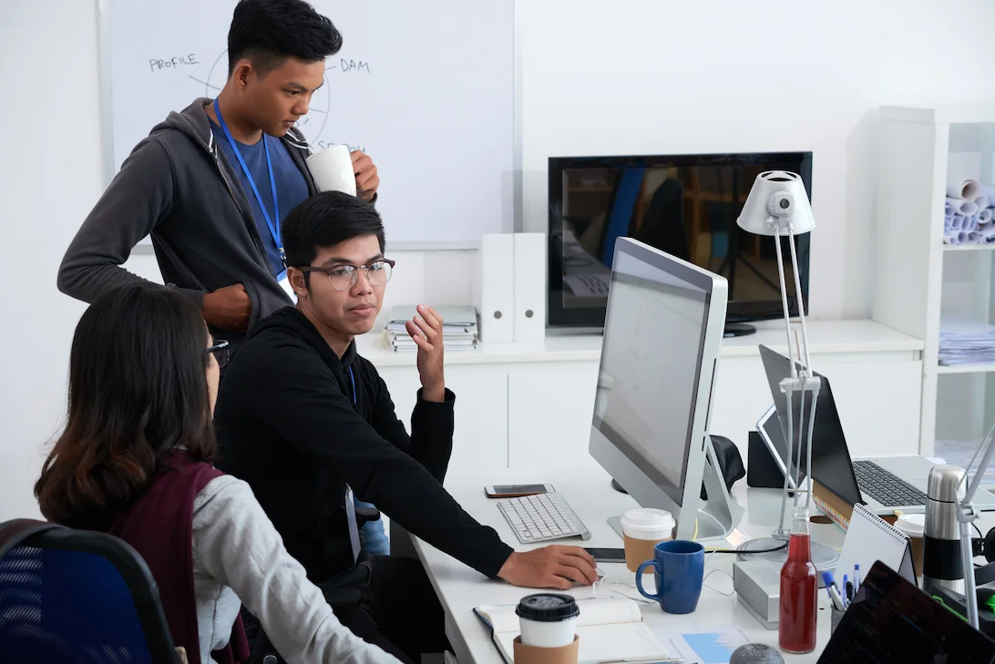 Three colleagues collaborating at a computer desk